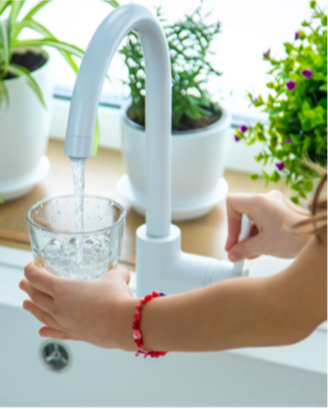 Woman filling a glass of water from the sink faucet. 